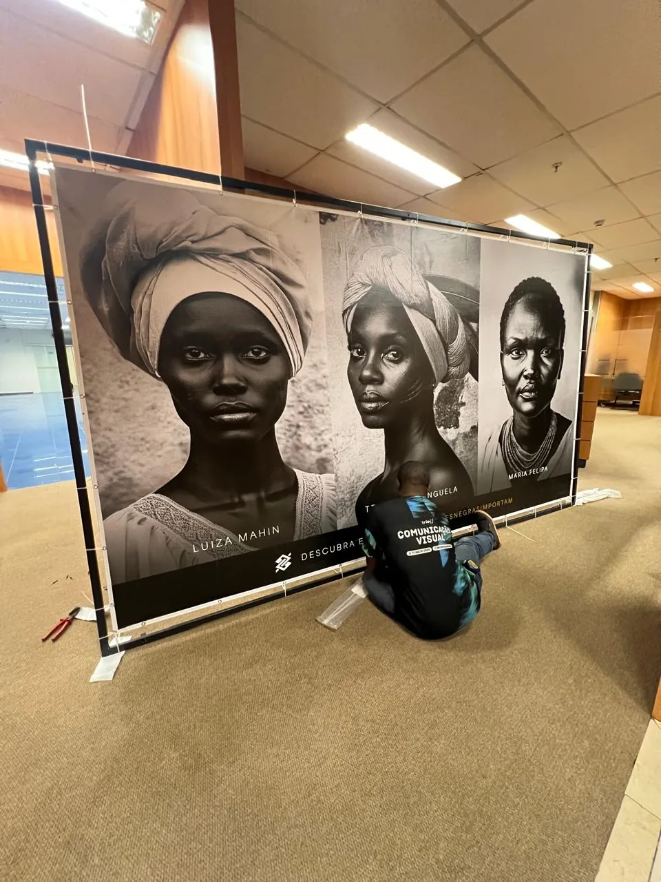 Painel fotográfico em preto e branco montado em estrutura para exposição.