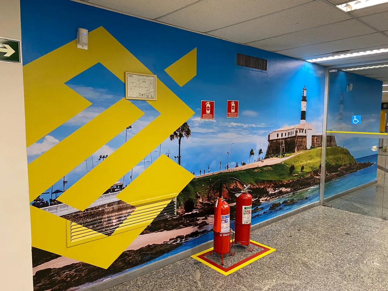 Parede de atendimento personalizada com paisagem de Salvador e identidade azul e amarela.