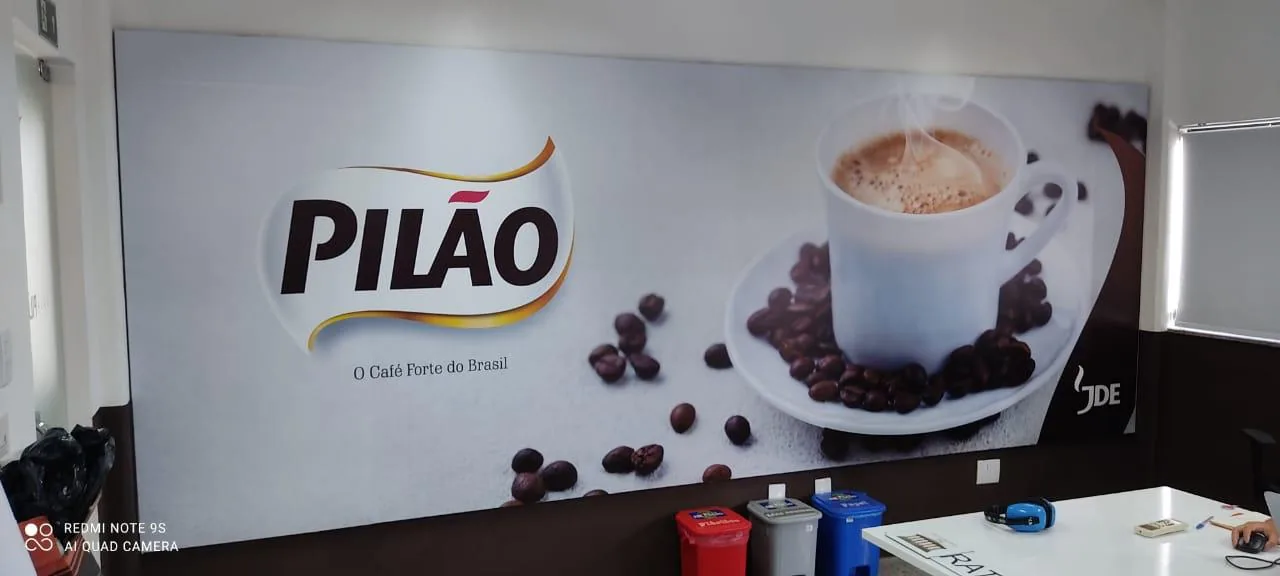 Painel panorâmico com xícara e grãos de café instalado em ambiente interno.